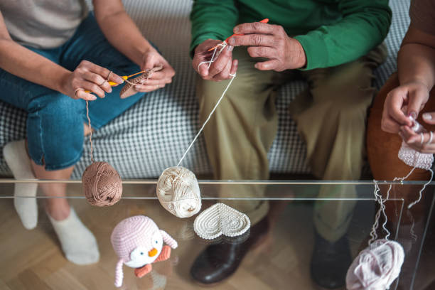 Three people crocheting together with yarn balls and small amigurumi—ideal for a shared crochet kit.
