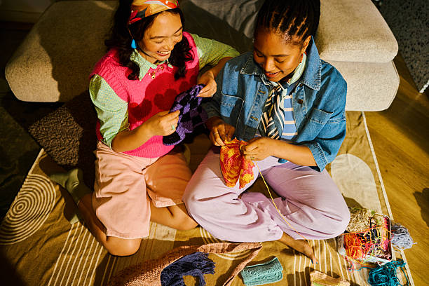 Three women laughing while crocheting in cozy café—perfect for social crafting with a crochet kit.
