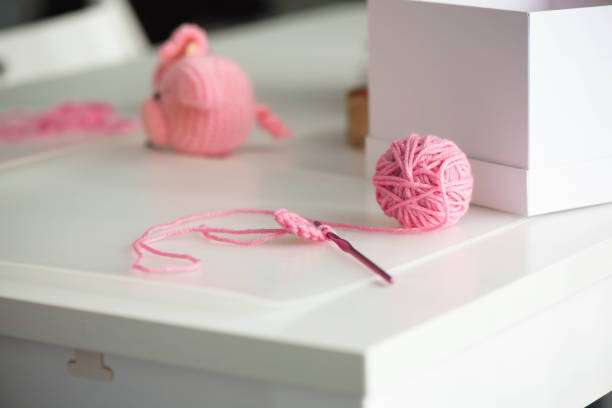 Pink yarn, hook, and partial pig toy from a beginner crochet kit.