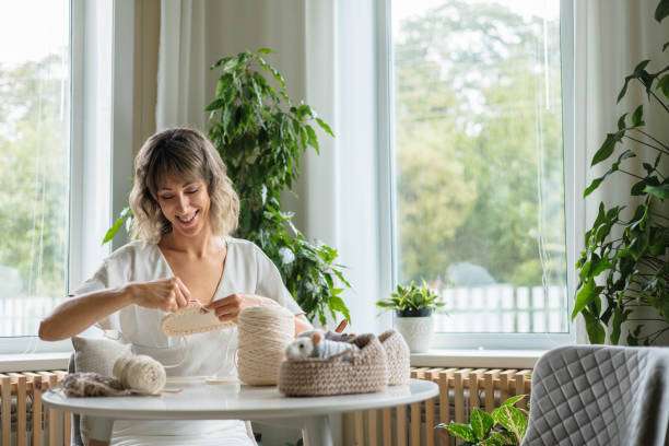 Smiling woman enjoying her craft project, using items from a crochet kit.