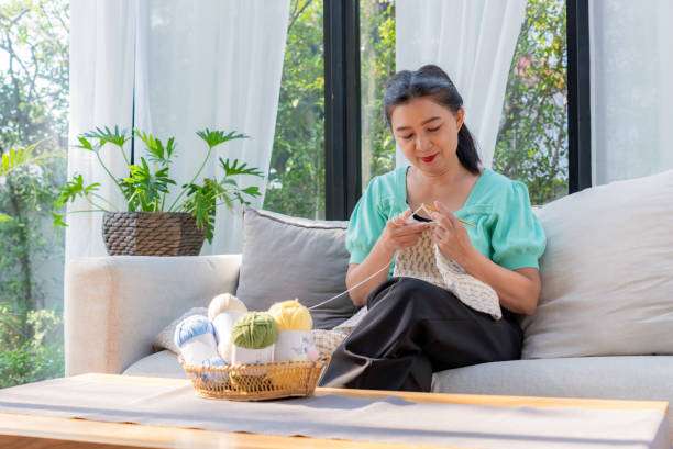 Woman relaxing on a sofa, happily using a colorful Crochet Kit to create.